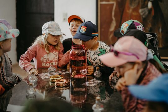 Kinder sitzen an einem Tisch und schauen in einem Krug
