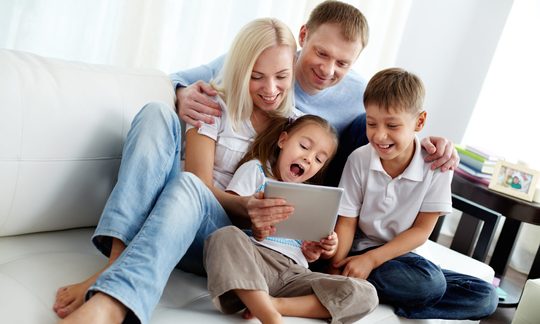 Familie mit 2 Kindern daheim vor tablet