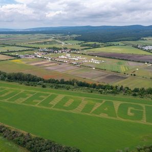 Feldtage-Schriftzug im grünen Feld bei St. Pölten mit Zelten und Gebäuden im Hintergrund.