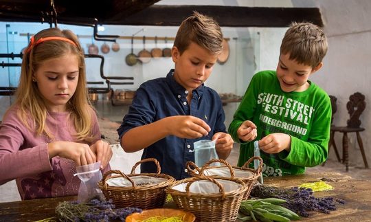 Drei Kinder mit Körben und Kräutern