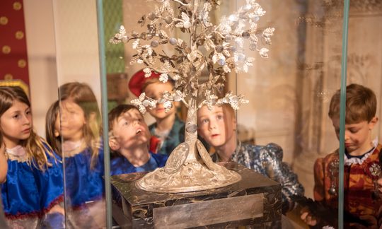 Kinder hinter Schaukasten mit Ausstelllungsstück