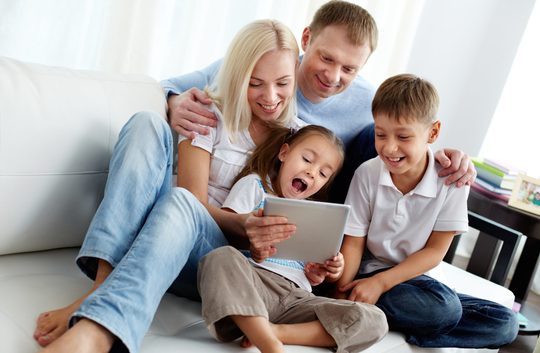 Familie mit 2 Kindern daheim vor tablet